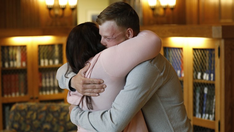 Lilly Ross, right, holds her 17-month-old son Leonard as she talks with face transplant recipient Andy Sandness, left, after their first meeting at the Mayo Clinic, Friday, Oct. 27, 2017, in Rochester, Minn.