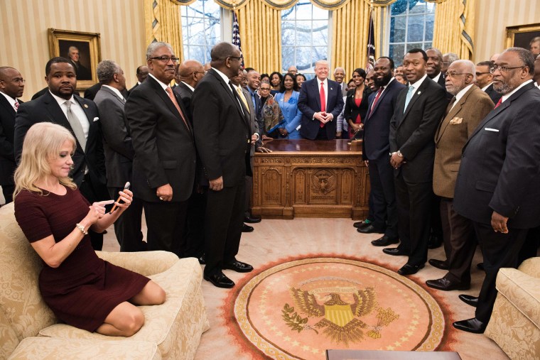 Image: Kellyanne Conway (L) checks her phone after taking a photo