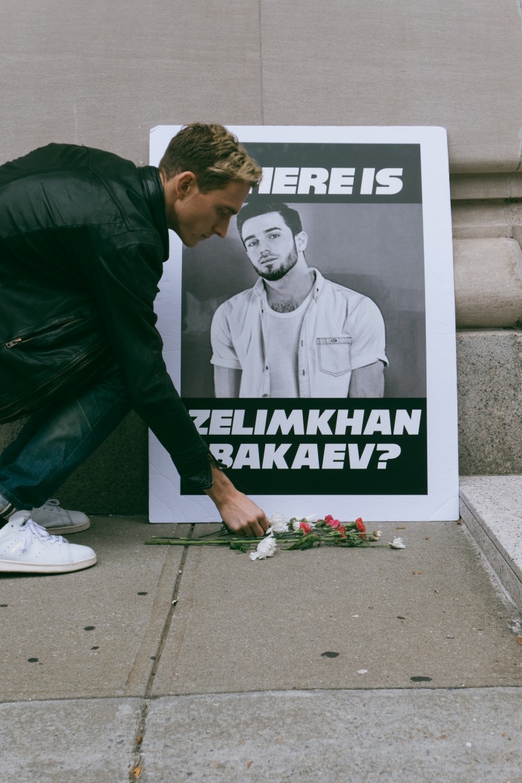 A member of Voices 4 Chechnya places a flower in front of an image of Zelimkhan Bakaev at a protest in front of the Russian consulate in New York City. 