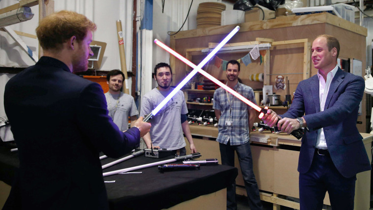 Prince William, Duke of Cambridge (C) and Britain's Prince Harry look at droid C3P0 from Star Wars as they visit the creature and droid department at Pinewood studios in Iver Heath, west of London on April 19, 2016.