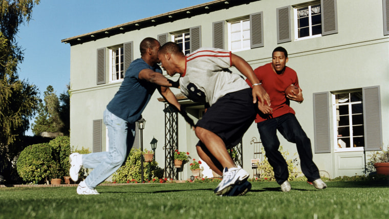 Three men playing football outside house