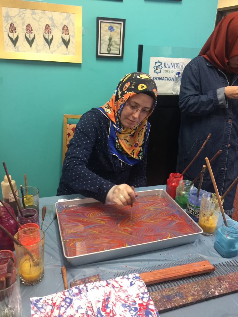 A woman uses water marbling techniques to create a piece of art at the Turkish Festival in Broken Arrow, Oklahoma.