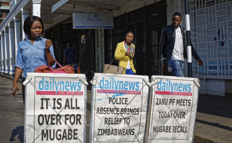 Image: Pedestrians walk past a newspaper stand in Harare, Zimbabwe