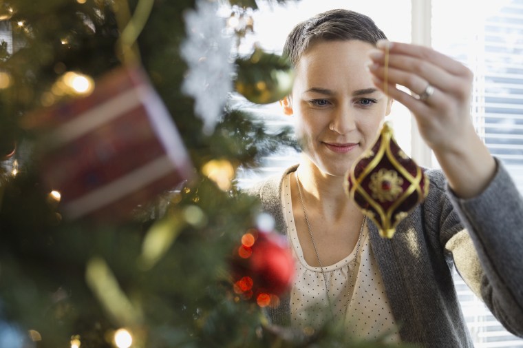 Image: A woman decorates a Christmas tree at home