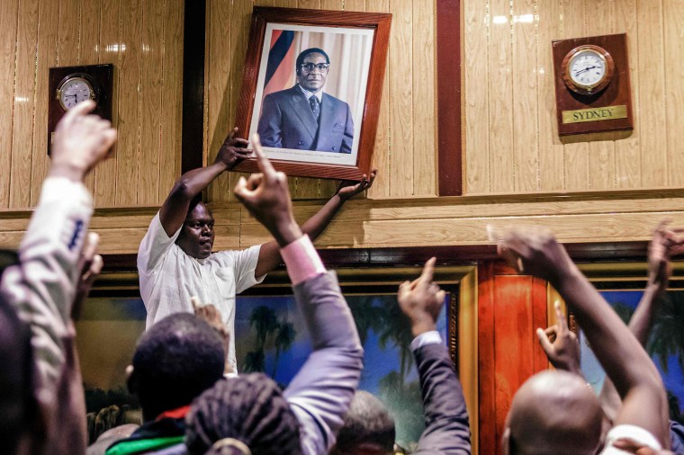 Image: People remove former Zimbabwean President Robert Mugabe's portrait  from the wall