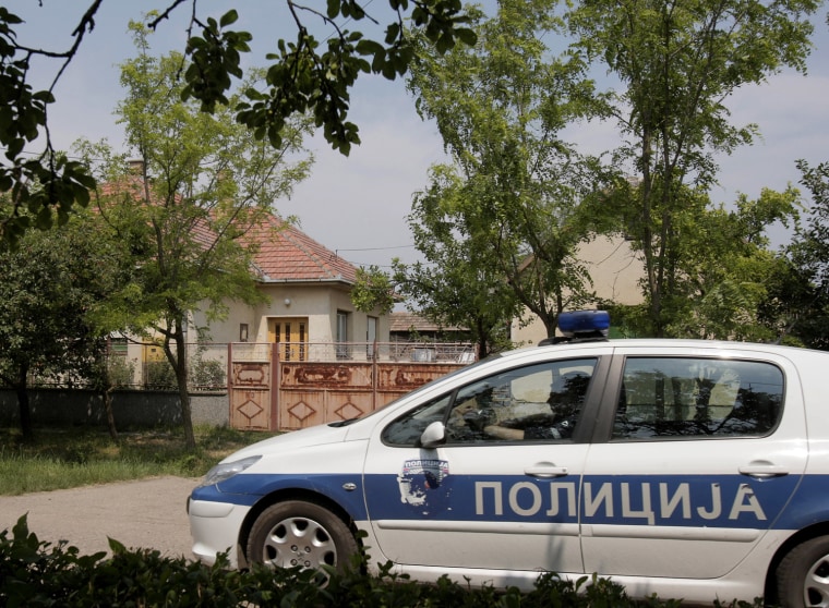 Image: A police car drives by the house, on left, where Ratko Mladic was found in the village of Lazarevo