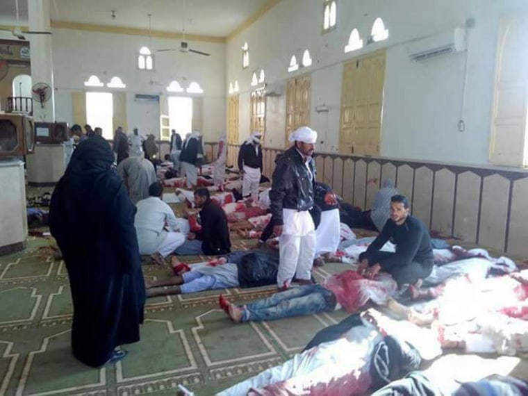 Image: People sit next to bodies of worshippers 