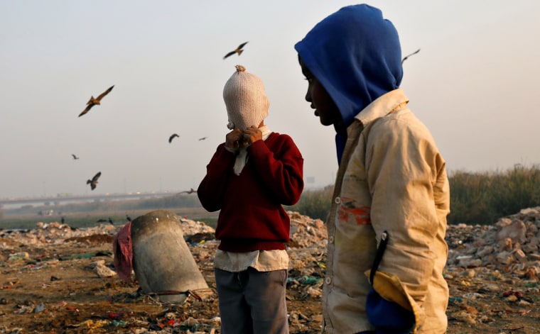 Image: A boy covers his face with a woollen hat on the banks of the Yamuna river in Delhi