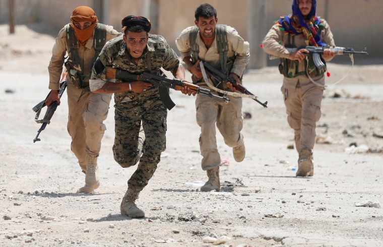 Image: Kurdish fighters from the People's Protection Units (YPG) run across a street in Raqqa, Syria