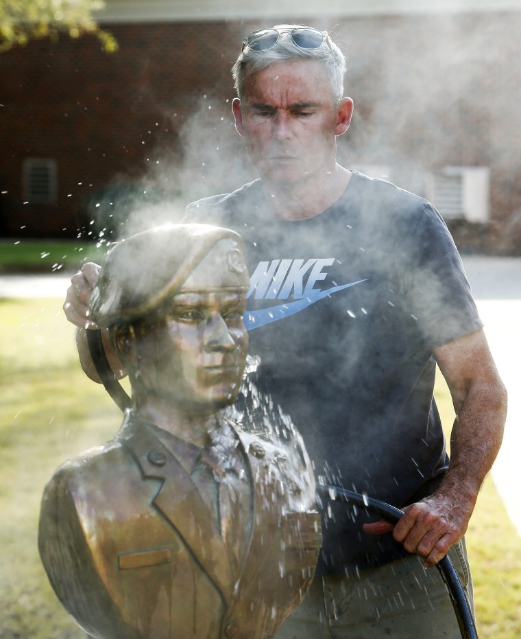 Image: Sculptor Lee Busby uses a water hose to cool the image of Mark Forester he sculpted