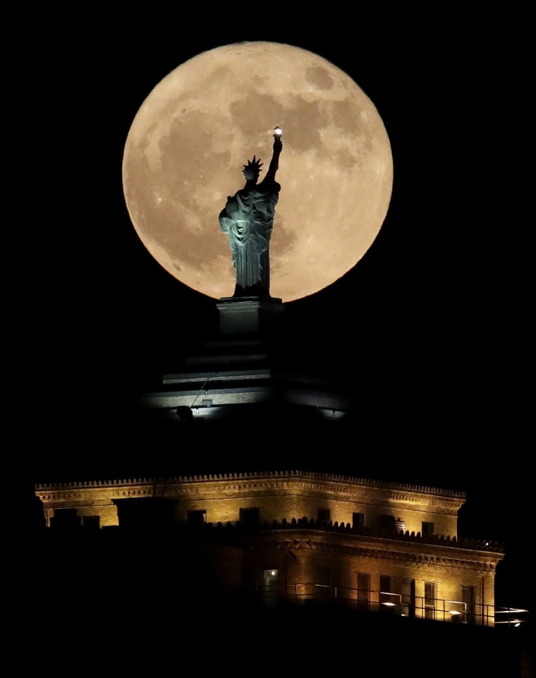 Image: A supermoon rises in front of a replica of the Statue of Liberty sitting atop the Liberty Building in downtown Buffalo