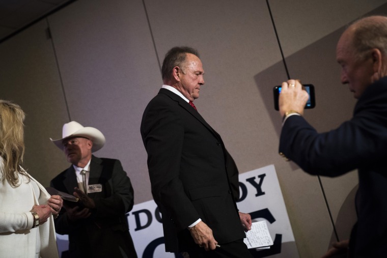 Image: Roy Moore takes his seat after speaking during a news conference