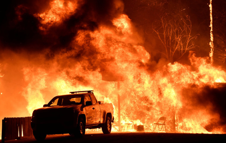 Image: Flames spread behind a vehicle from a Santa Ana wind-driven brush fire called the Thomas Fire in Santa Paula, California