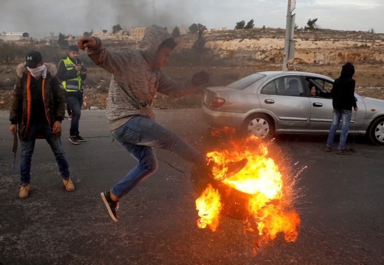 Image: A Palestinian kicks a burning tire during clashes with Israeli troops at a protest against U.S. President Donald Trump's decision to recognize Jerusalem as Israel's capital, near the Jewish settlement of Beit El, near the West Bank city of Ramallah