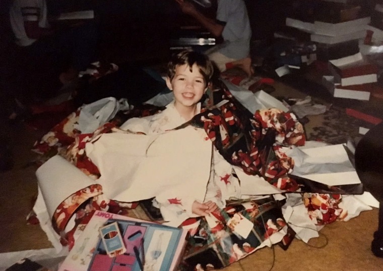 A young Dylan Dreyer surrounded by gifts at Christmas.