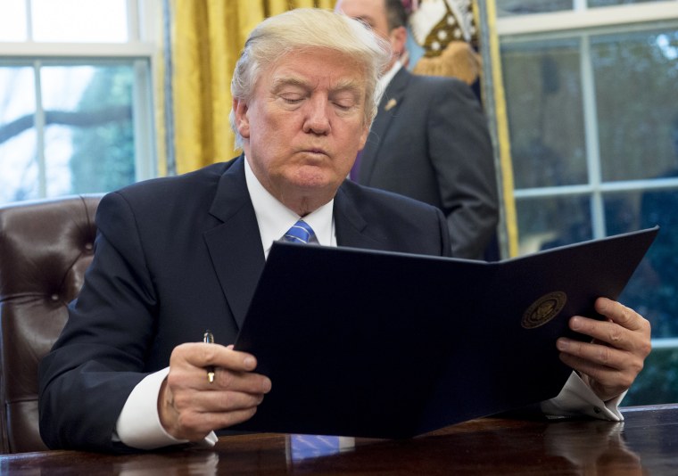 Image: U.S. President Donald Trump reads an executive order