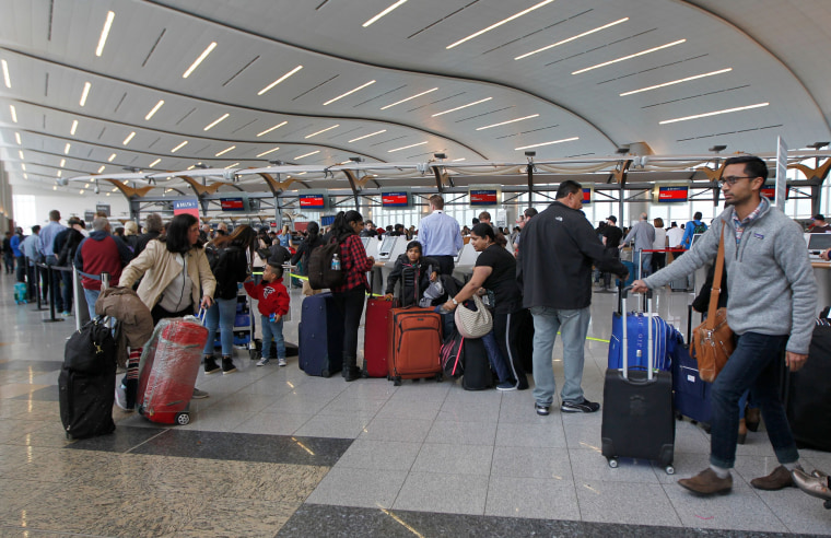 Image: Airline passengers arrive to stand in line at the Delta Airlines international counter