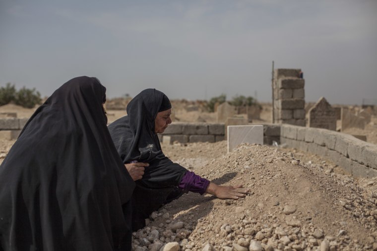 Image: Fatima Ahmed Aswad cries as she touches the grave of her 15-year-old daughter, Sana, in Mosul