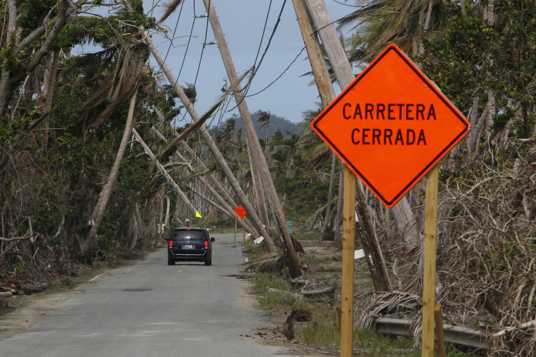 Image: A car drives under downed power lines in the aftermath of Hurricane Maria