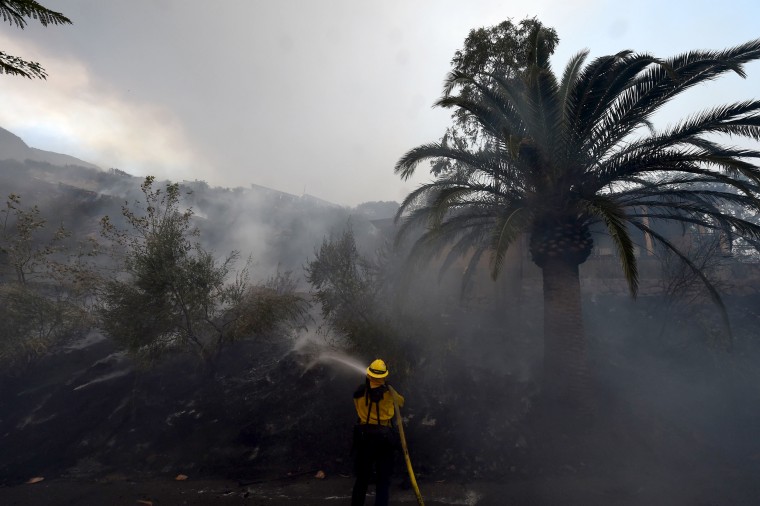 Image: A firefighter puts out hotspots on a smoldering hillside in Montecito, California as strong winds blow smoke and embers inland on Dec. 16, 2017 at the Thomas Fire.