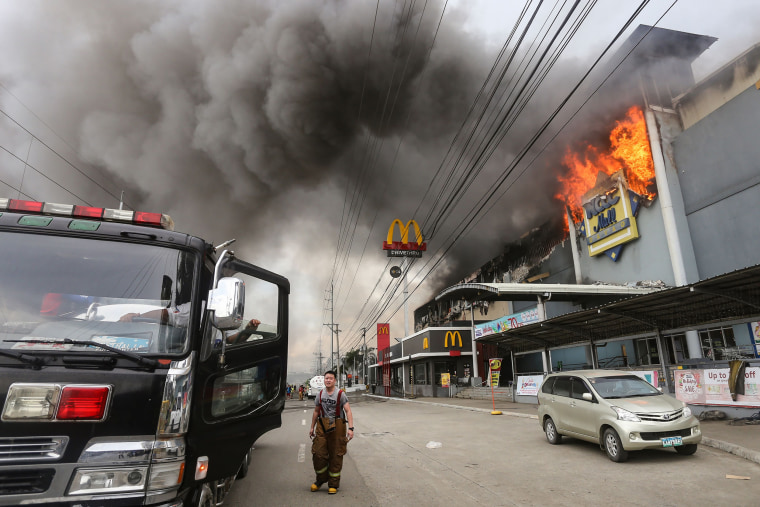 Image: A firefighter stands in front of a burning shopping mall in Davao City