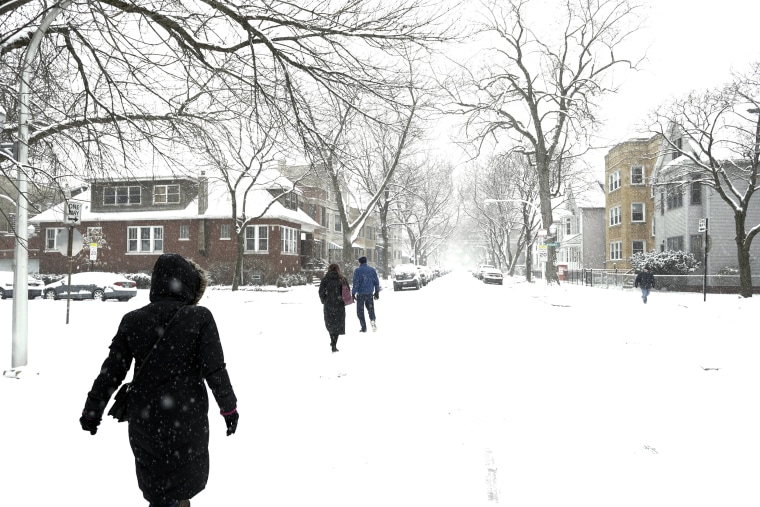 Image: People walk on snow covered streets in the Lakeview neighborhood of Chicago