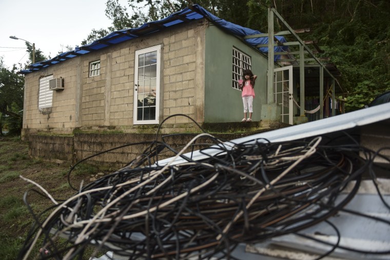 In this Dec. 22, 2017 photo, six year old Melanie Oliveras Gonz?lez stand on the porch of her house, in front of a handful of electric cables knocked down by the winds of Hurricane Maria, in Morovis, Puerto Rico.