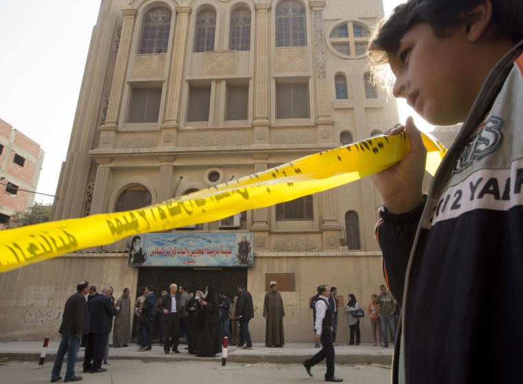 A boy holds yellow tape surrounding the site in front of Mar Mina church, in Helwan, Cairo on Dec. 29, 2017.