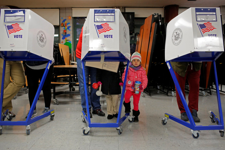 Image: Myla Gibson, 3, waits as her father Ken Gibson fills out a ballot for the U.S presidential election at the James Weldon Johnson school in the East Harlem neighbourhood of Manhattan, New York City