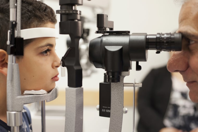 Image: A doctor checks the eyes of a patient who received a blindess gene therapy treatment