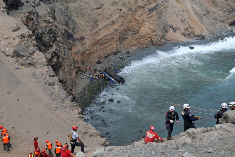Image: Rescue workers  and police work at the scene after a bus crashed with a truck and careened off a cliff along a sharply curving highway north of Lima