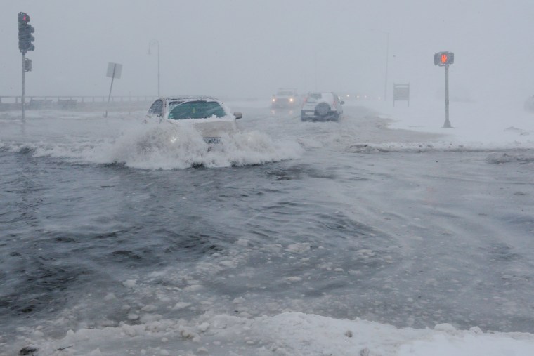 Image: Drivers make their way along the flooded Beach Road after the ocean overtopped the seawall in the Boston suburb of Lynn
