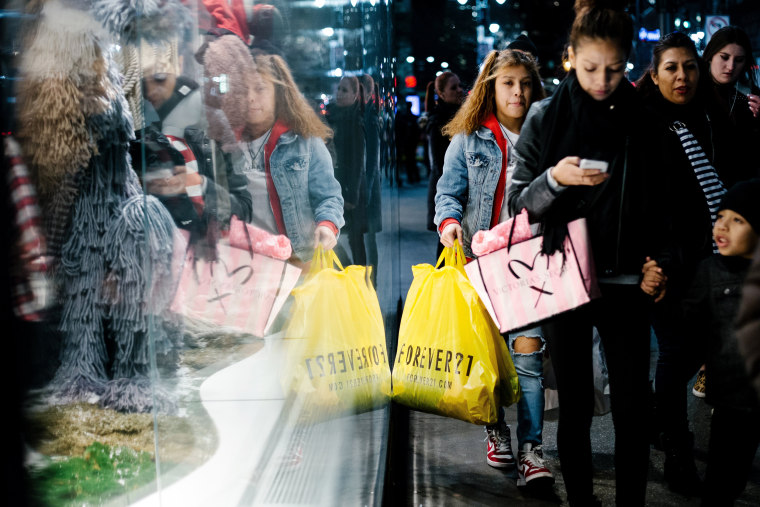 Image: People carry shopping bags outside a shopping mall