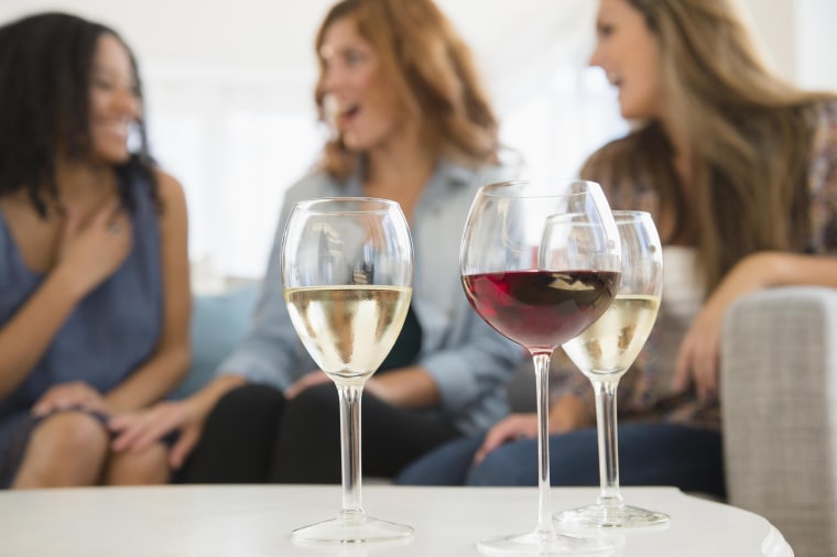 Image: Women drinking wine and talking on sofa in living room