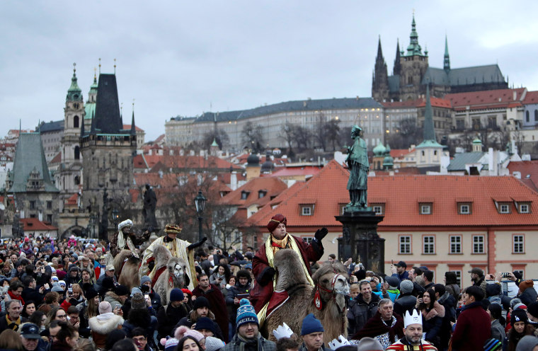 Image: Men dressed as the Three Kings greet spectators as they ride camels during the Three Kings procession across the medieval Charles Bridge in Prague