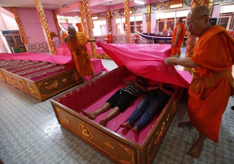 Image: Monks cover worshipers lying in coffins in suburban Bangkok