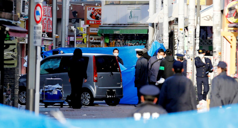 Image: Policemen stand next to a car which plowed into pedestrians on New Year day in Tokyo