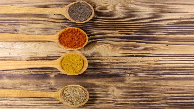 Assorted spices in wooden spoons on a table.