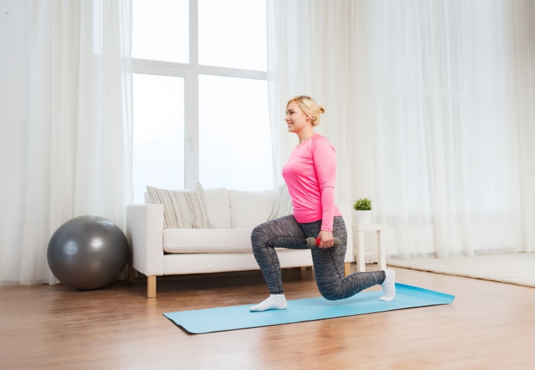 smiling woman with dumbbells exercising at home