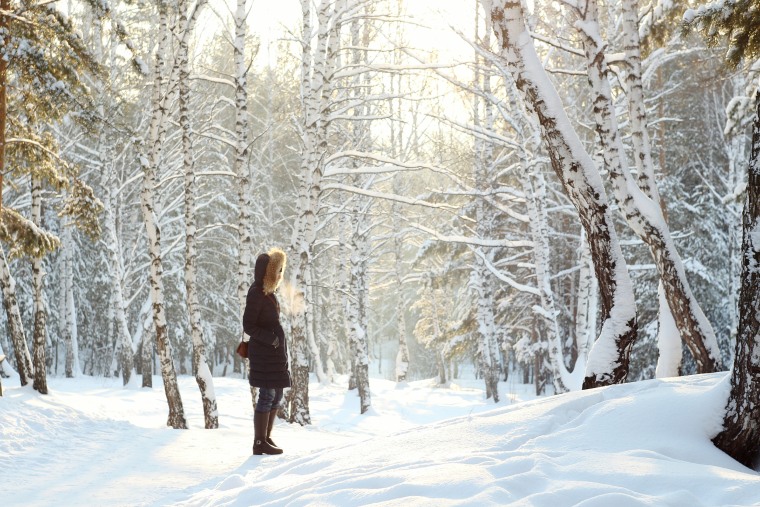Image: Side View Of Woman Standing Against Bare Trees On Snow Covered Field At Forest
