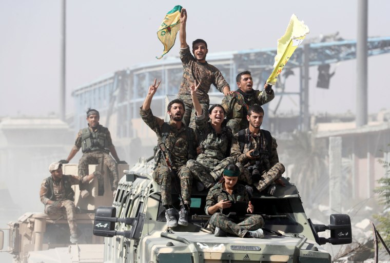 Image: Syrian Democratic Forces (SDF) fighters ride atop of military vehicles as they celebrate victory in Raqqa
