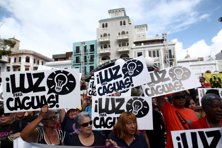 Image: People hold signs during a protest demanding that authorities fix the electrical grid which was mostly destroyed after Hurricanes Irma and Maria hit the island in September, in San Juan