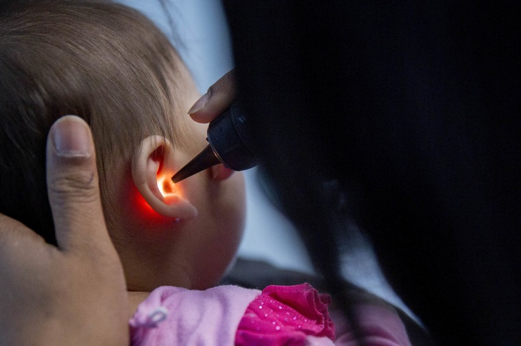 Image: A pediatrician examines an infant's ear in Takoma Park, Maryland, on April 8, 2015.