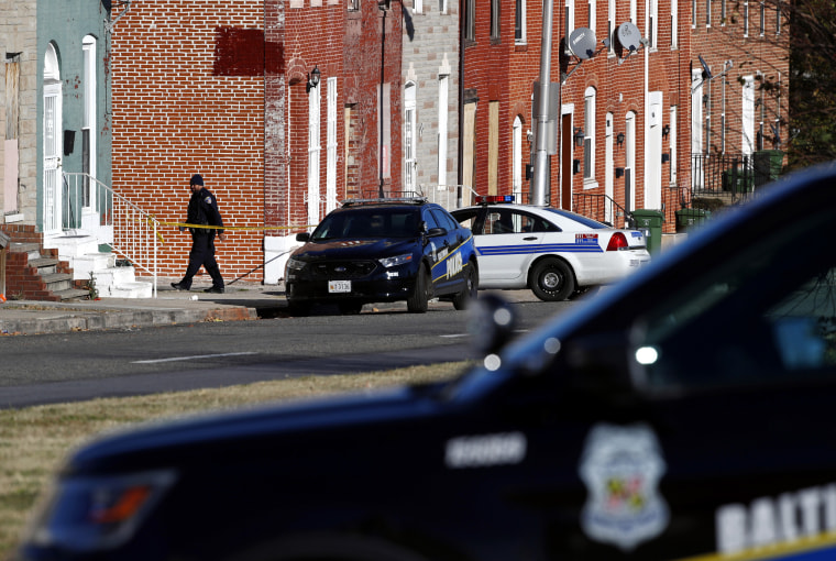 Image: An officer walks behind a police line near the scene of a shooting
