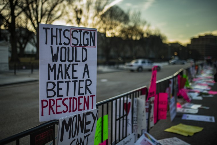 Image: Signs left by protesters lay on a fence in front of the White House.