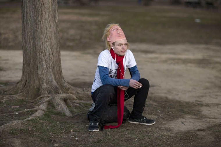 Image: A protester takes a break from wearing his Donald trump mask while sitting in front of the White House.