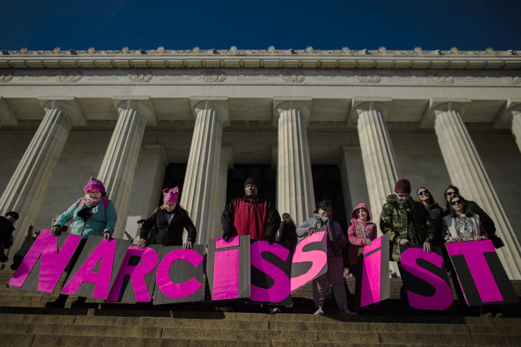 Image: People carry placards reading \"narcissist\" as they gather around Lincoln Memorial.