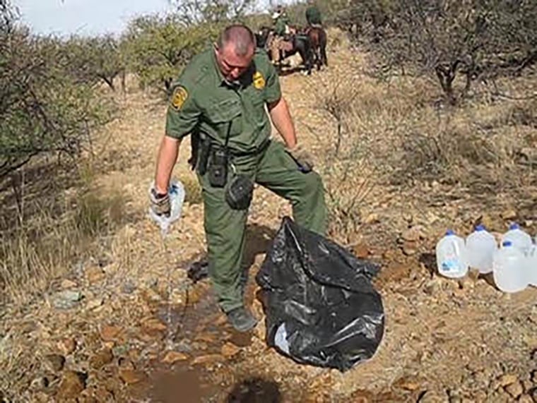 Image: A Border Patrol agent empties a water bottle