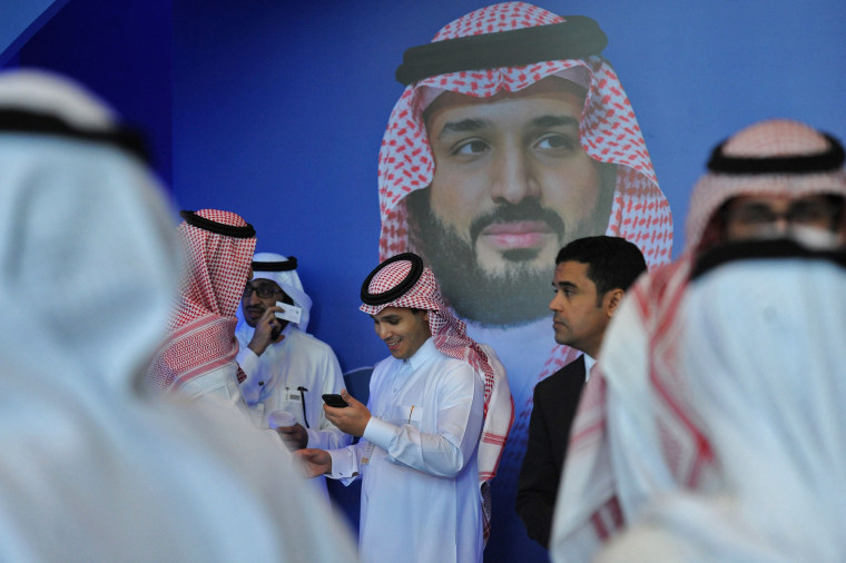 Image: Saudi men chat in front of a poster of Saudi Crown Prince Mohammed bin Salman 