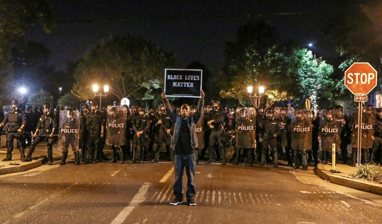 A Black Lives Matter protester stands in front of St. Louis Police Department officers equipped with riot gear in St. Louis